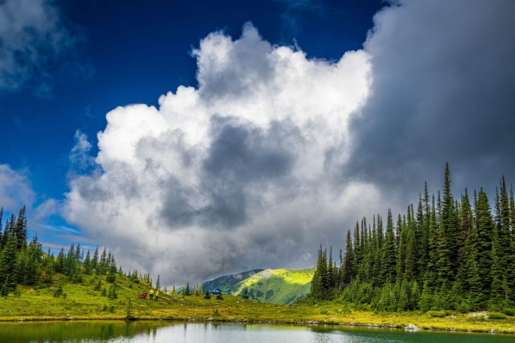 ikers beside alpine lake in British Columbia wilderness