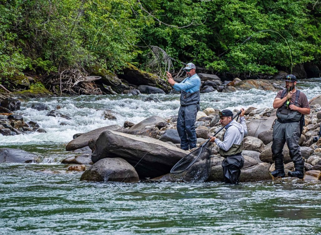 angler casting fly rod on remote freestone river in British Columbia wilderness