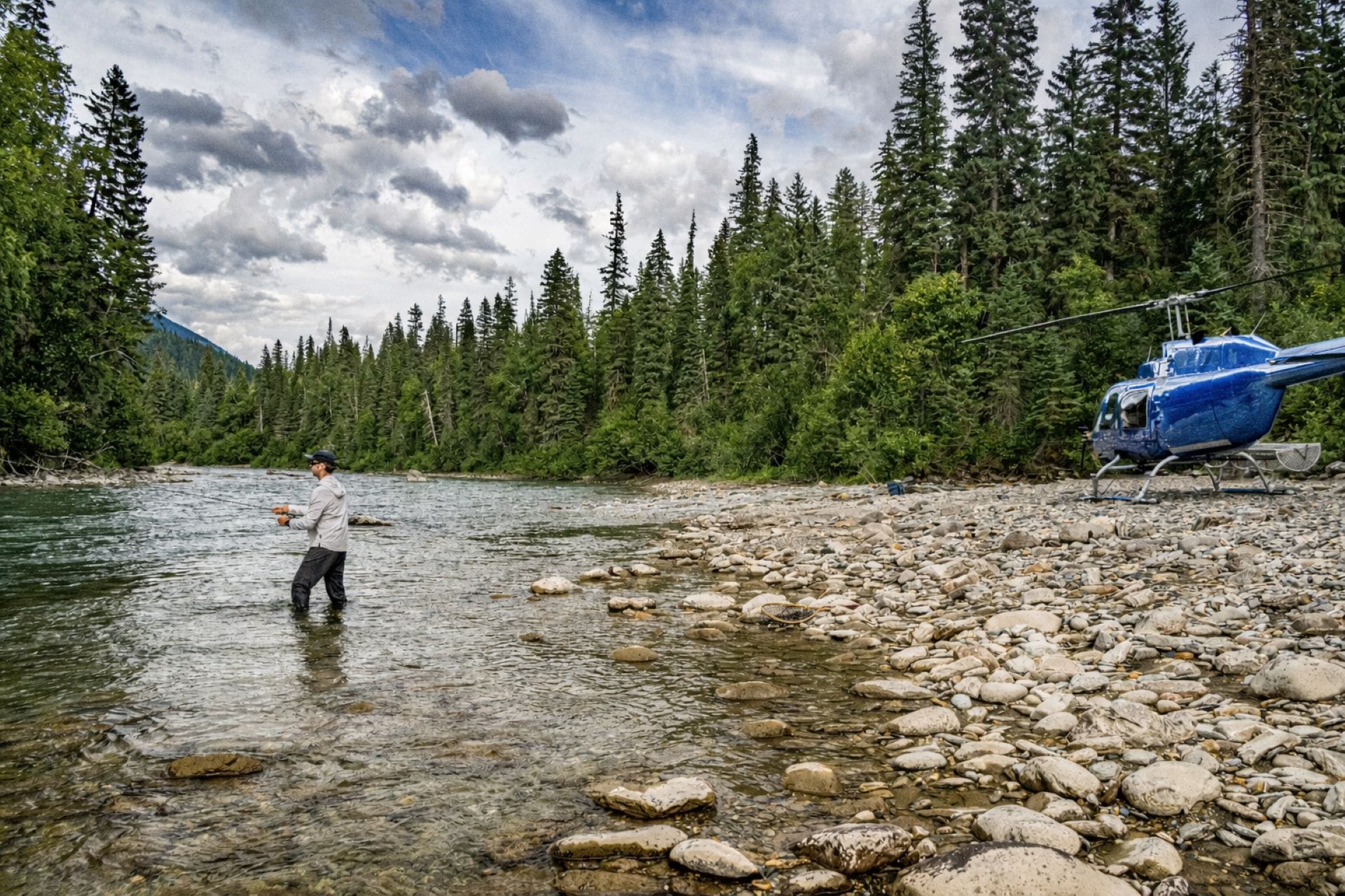 angler-fishing-next-to-helicopter-british-columbia Anger fishing in freestone river next to a helicopter in British Columbia