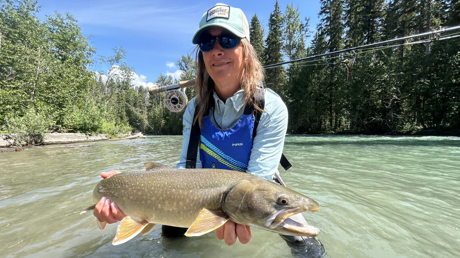 Angler holding bull trout caught fly fishing in BC wilderness